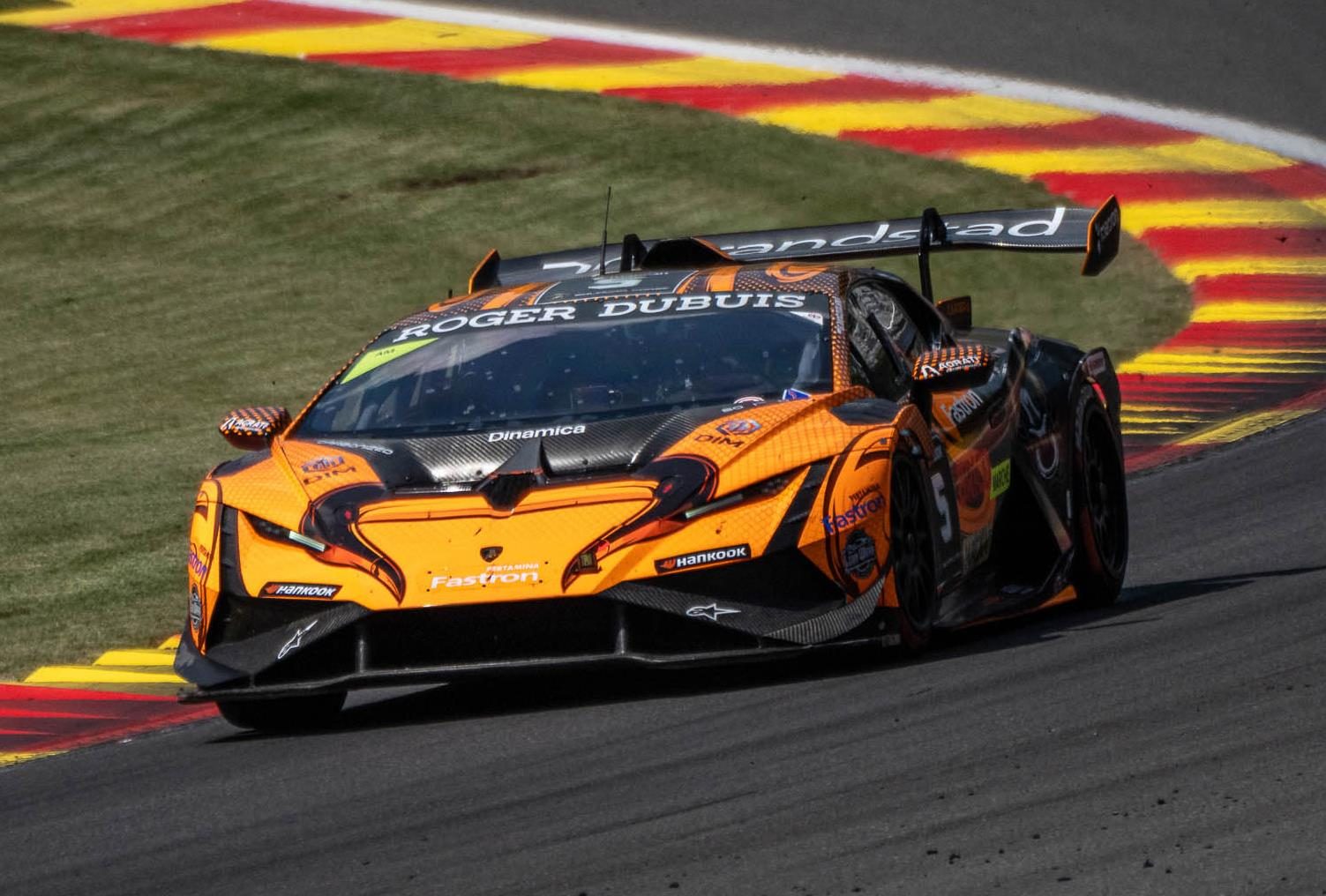 An orange and black Lamborghini Huracán Super Trofeo EVO2 race car number 55 cornering on a racetrack under clear skies