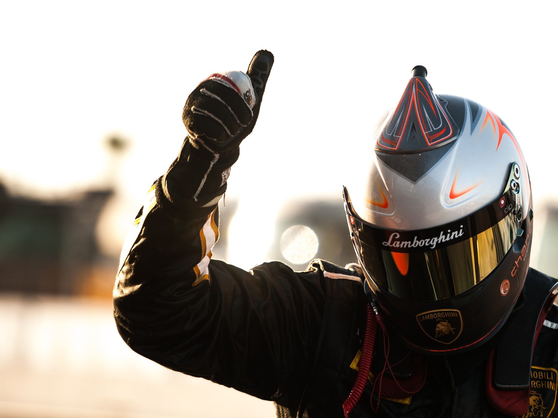Lamborghini Super Trofeo driver in black racing suit and silver helmet giving a thumbs up after a successful race at Sebring