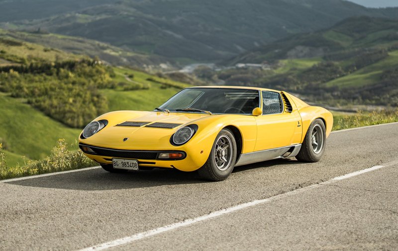 Yellow Lamborghini Miura SV on a winding mountain road, the car that started the Super Veloce lineage in 1971